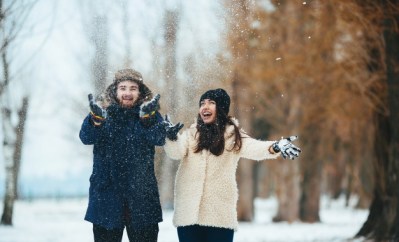 smiling-couple-playing-with-snow-field_1153-1427
